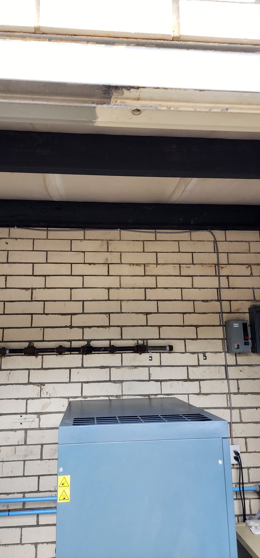 A blue box is sitting in front of a white brick wall.