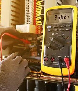 A person is using a digital multimeter to measure voltage.