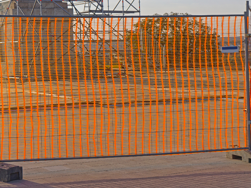 An orange fence is sitting on the side of the road
