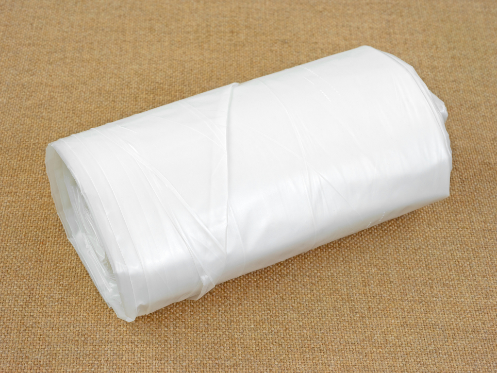 A roll of plastic bag is sitting on a carpet.