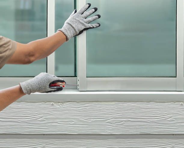 A person wearing gloves is measuring a window with a tape measure.