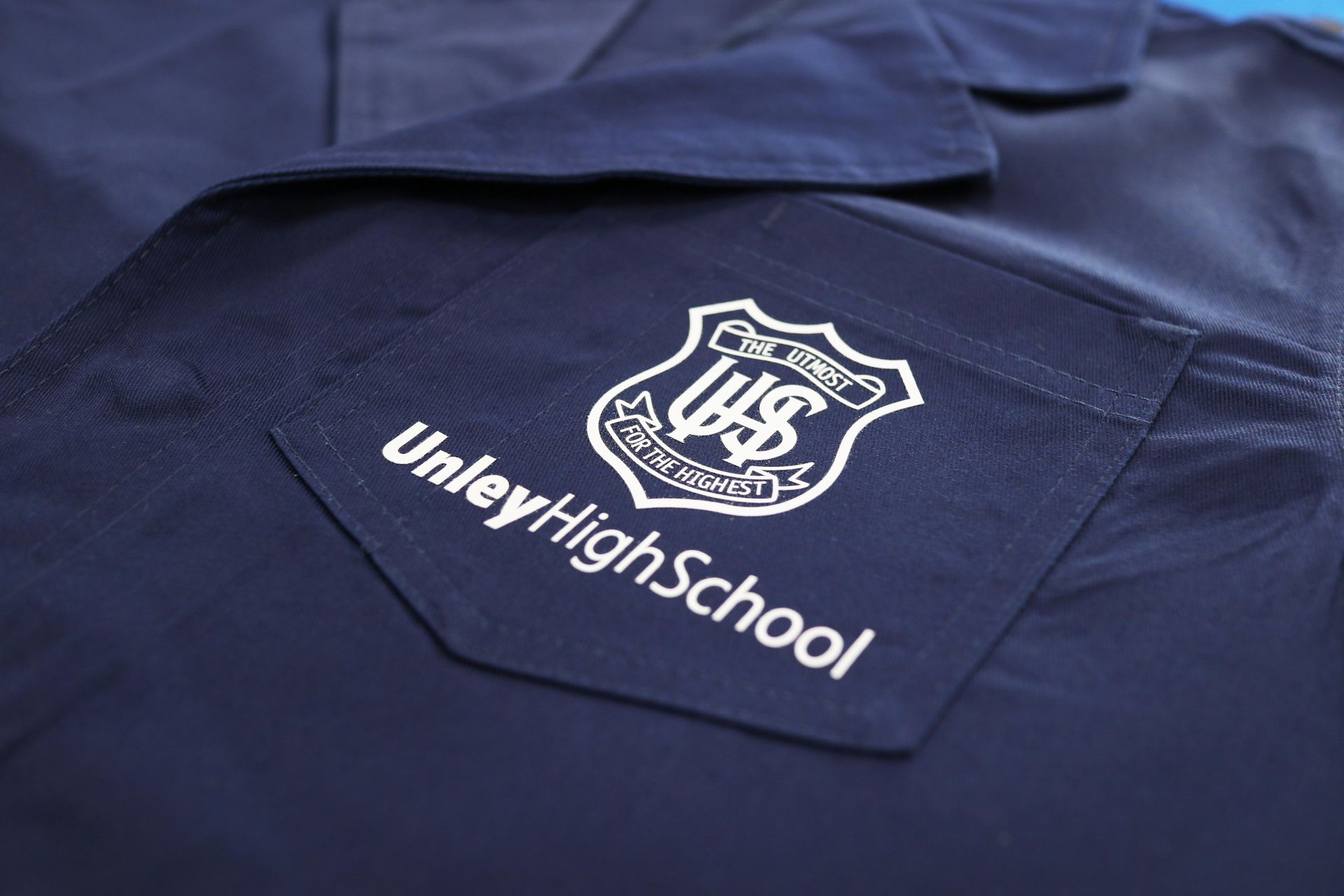 Navy blue school shirt with printed Unley High School logo on the pocket.