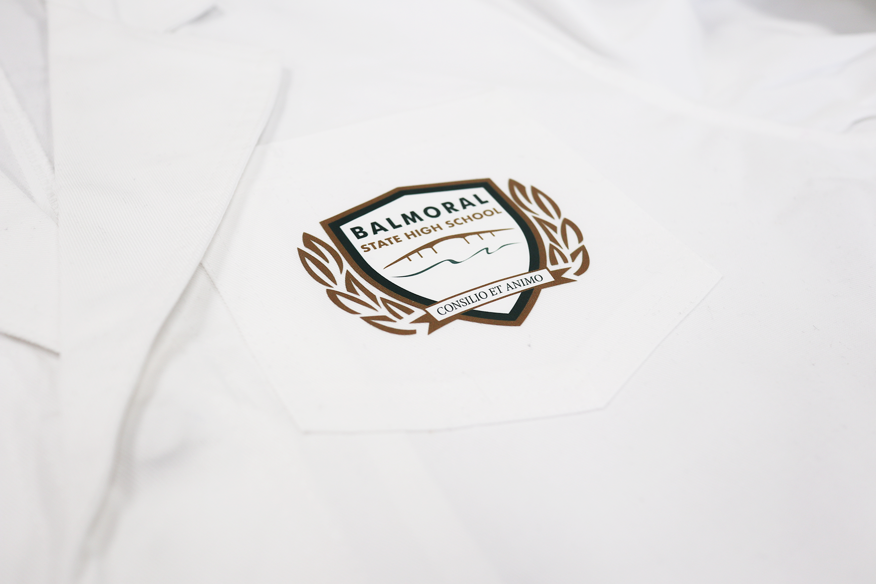 White lab coat pocket with Balmoral State High School logo.
