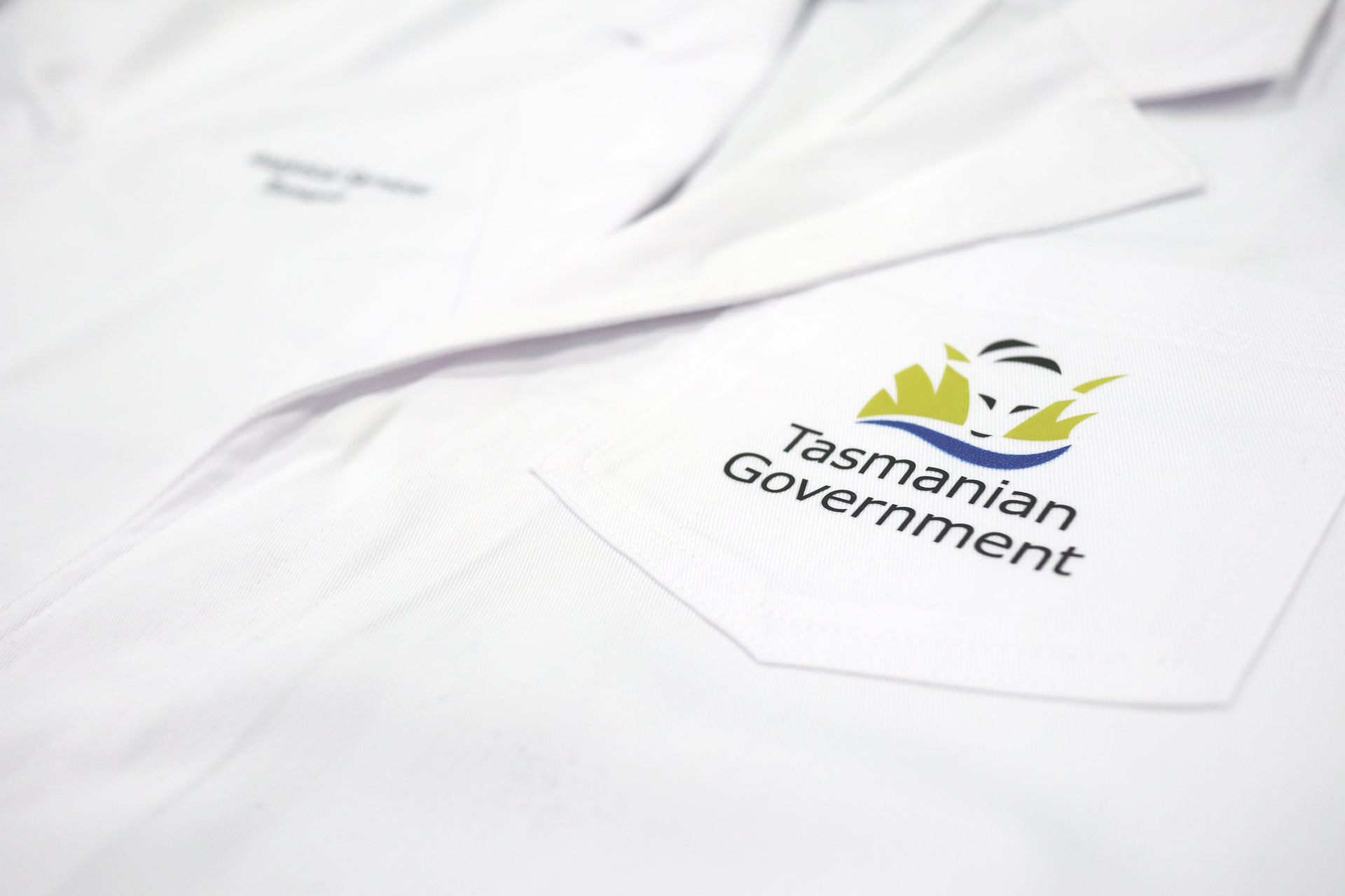 White lab coat with Tasmanian Government logo on pocket.