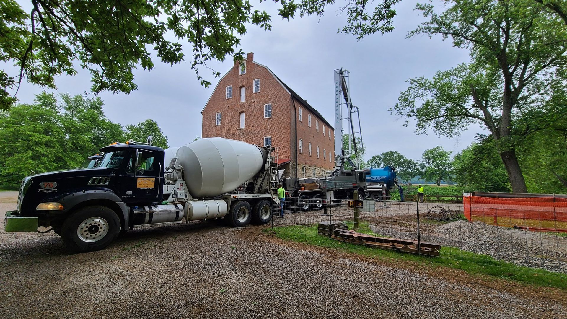 A concrete mixer truck is parked in front of a brick building.