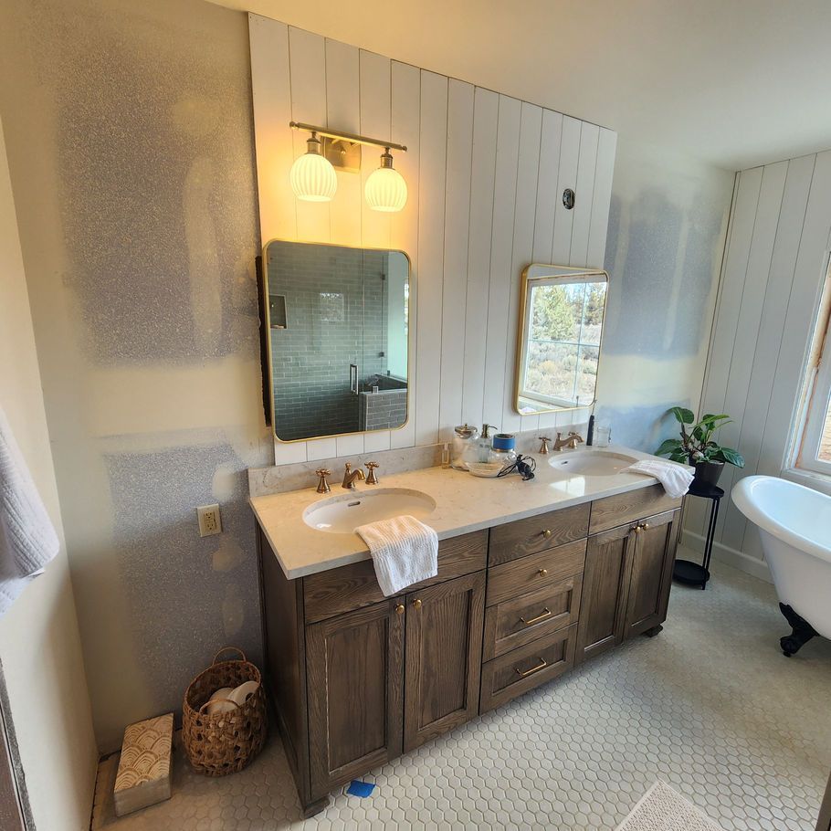 Bathroom with a double vanity, wood cabinets, white countertop, and a mirror above each sink. White shiplap wall.