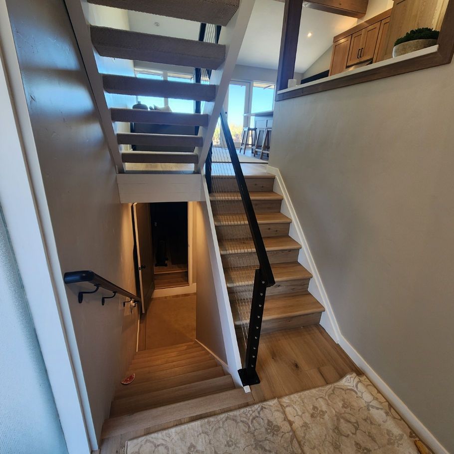 Staircase with wooden steps and black metal railing leads up and down to different levels within a house.