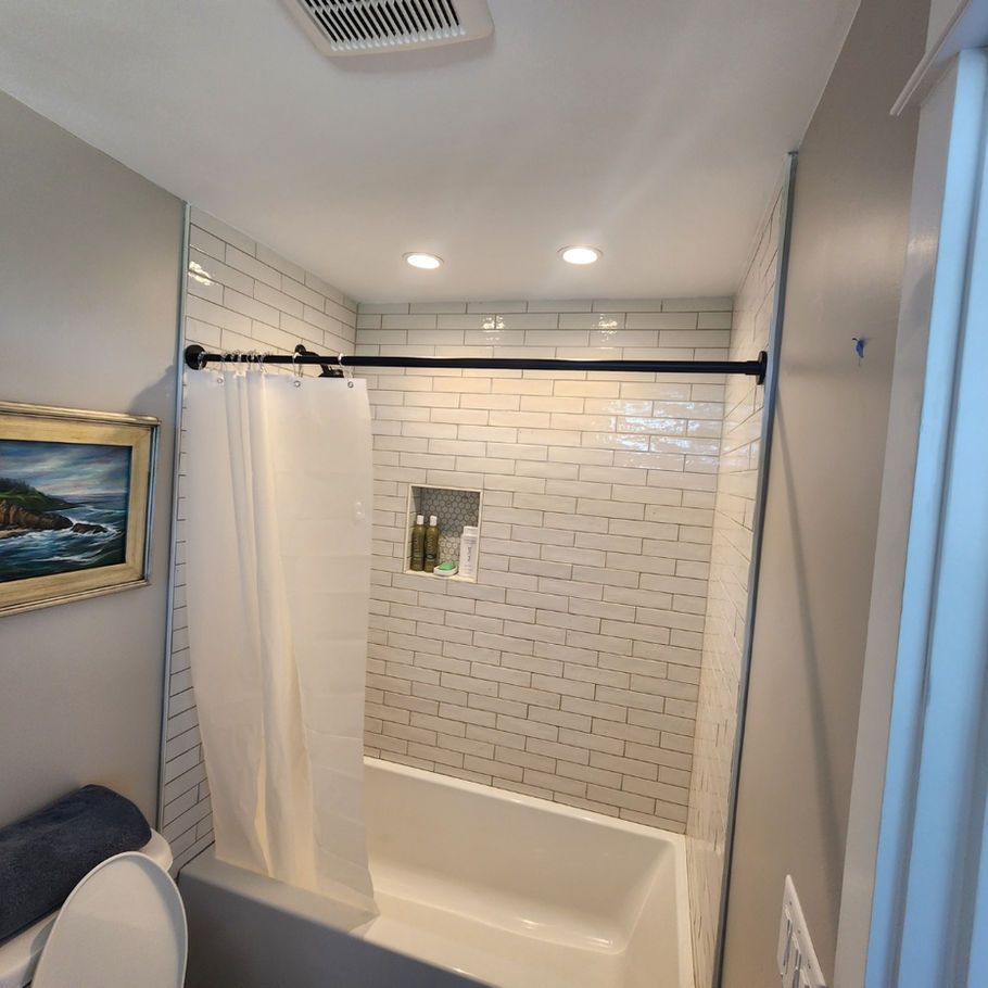 Bathroom with white subway tile shower, white tub, and gray walls. A white shower curtain is pulled across the shower.
