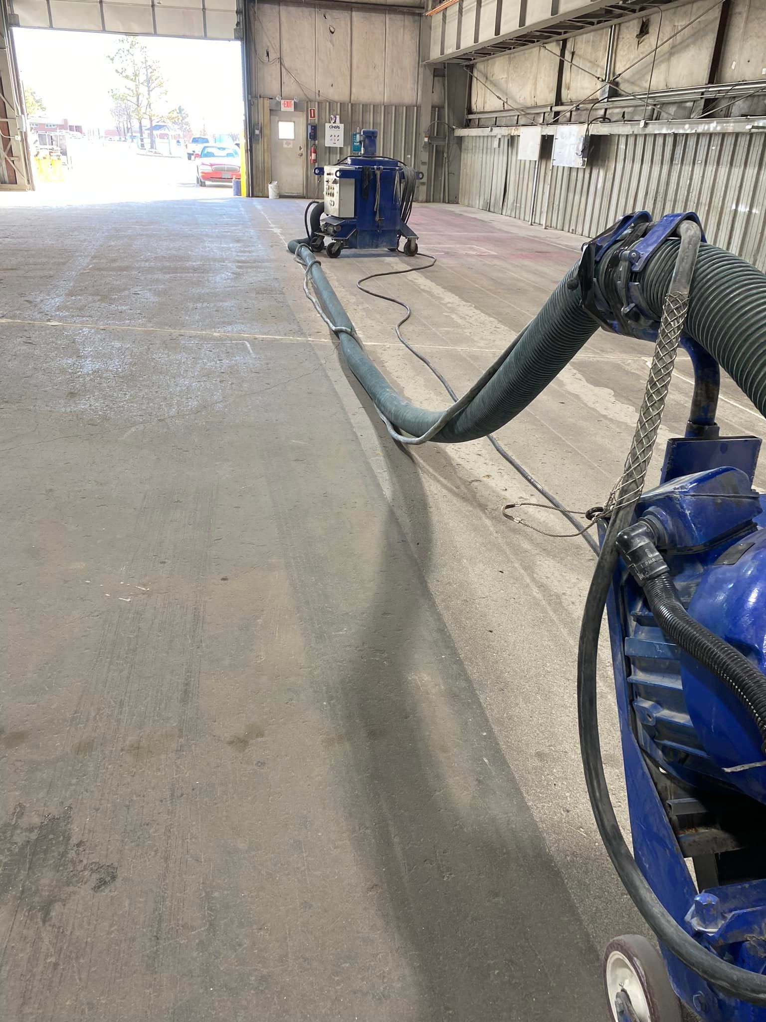 A vacuum cleaner is being used to clean a concrete floor in a garage.