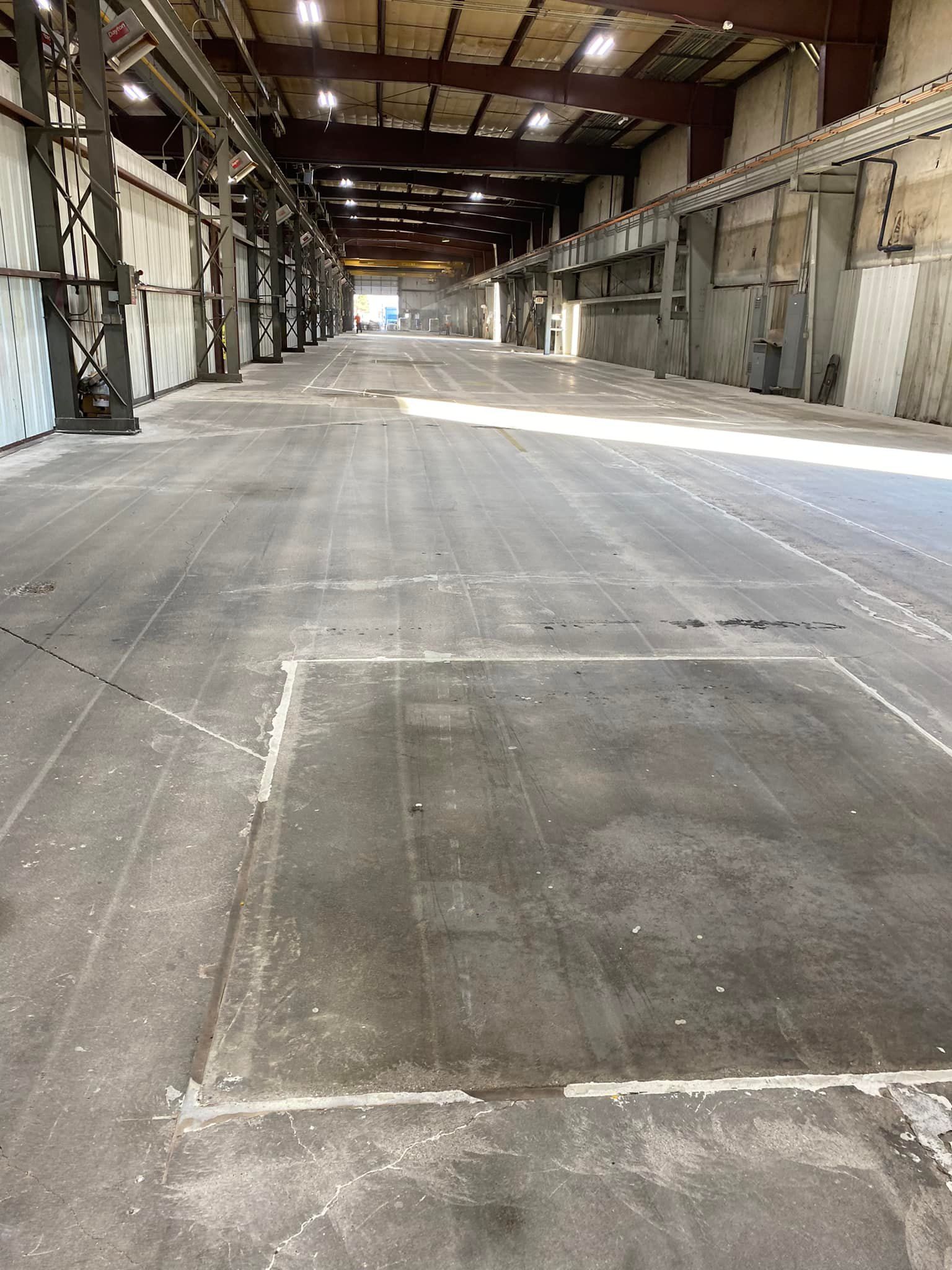 A large empty warehouse with a concrete floor and a square in the middle.