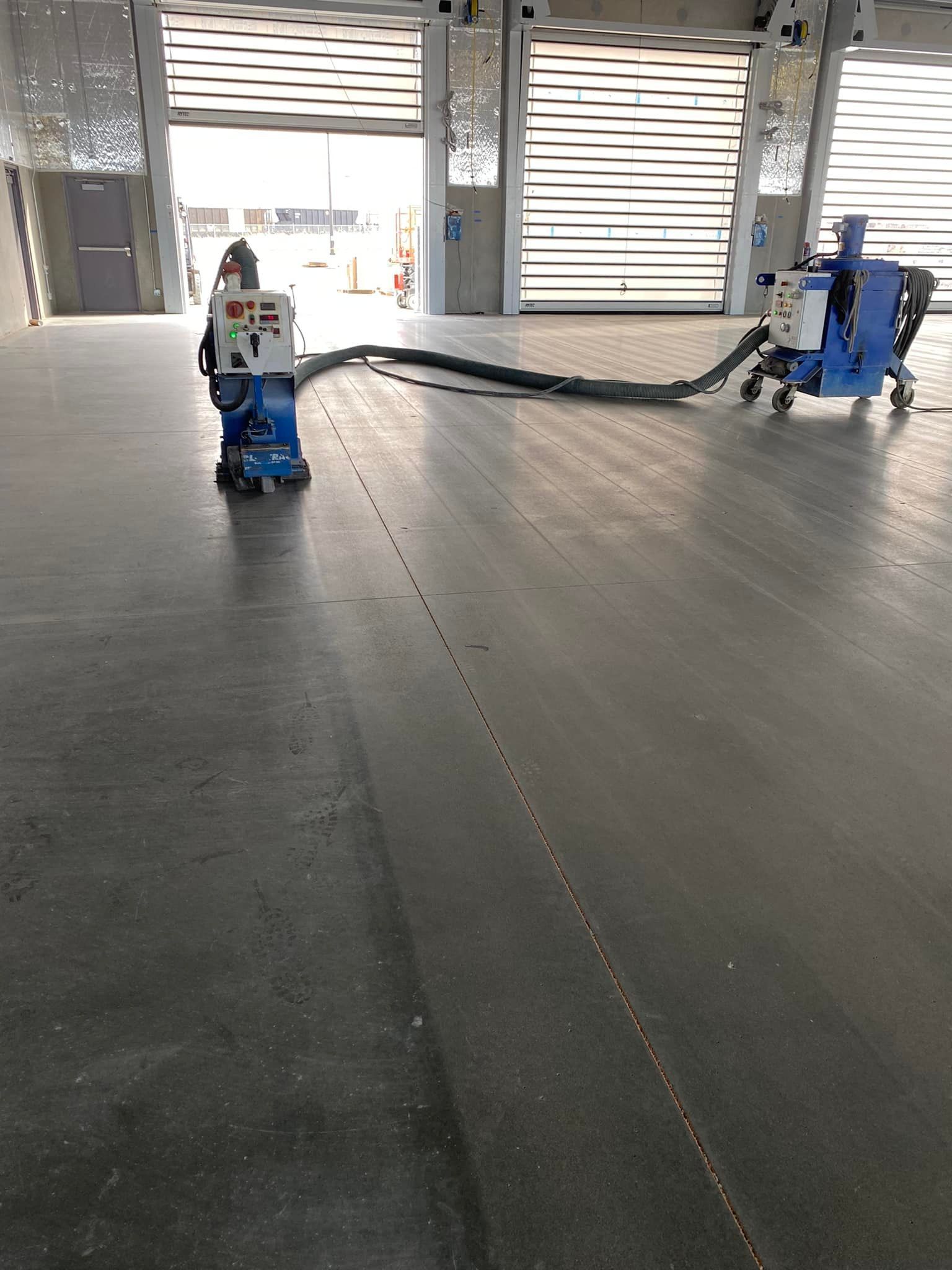 A machine is cleaning a concrete floor in a warehouse.