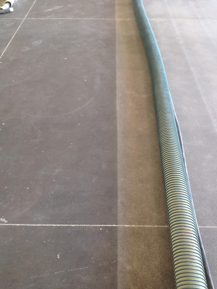 A green hose is laying on a tiled floor