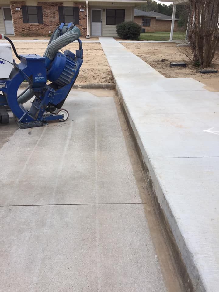 A blue machine is sitting on a sidewalk next to a house.