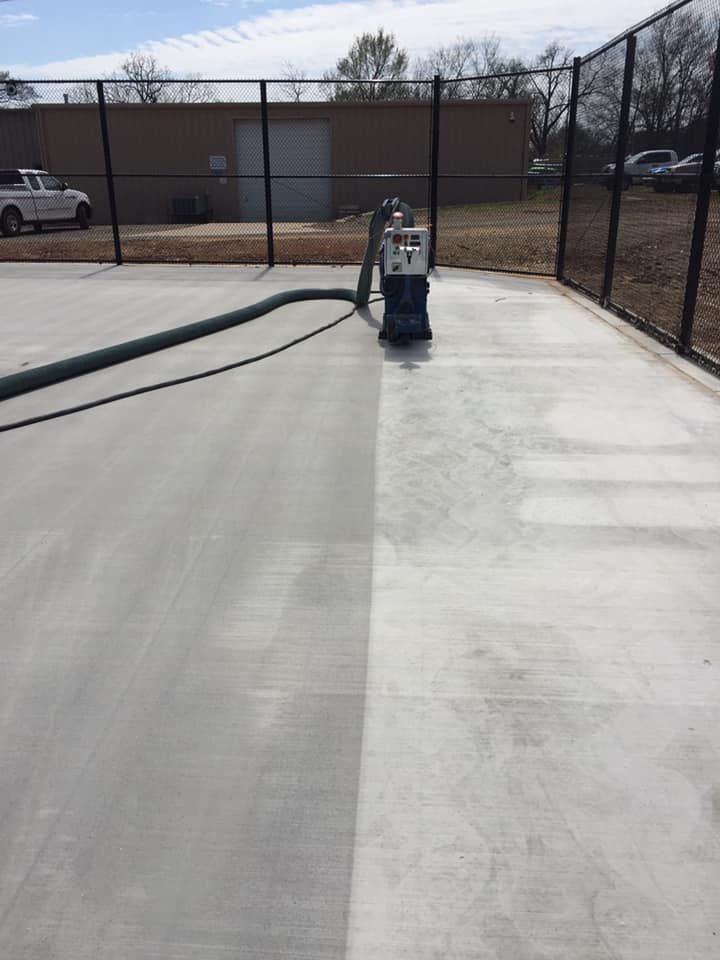 A concrete surface is being cleaned with a machine.