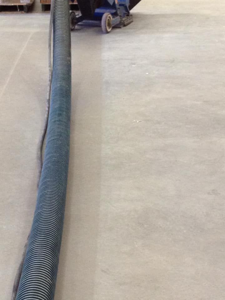 A vacuum cleaner is cleaning a concrete floor in a warehouse.