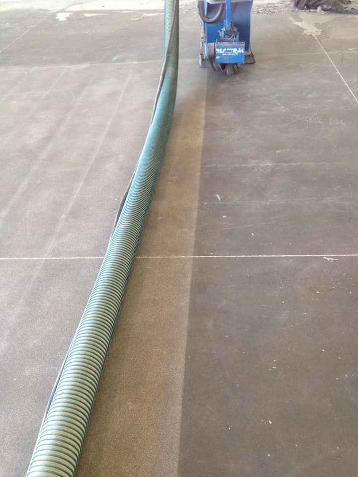 A vacuum cleaner is being used to clean a concrete floor.