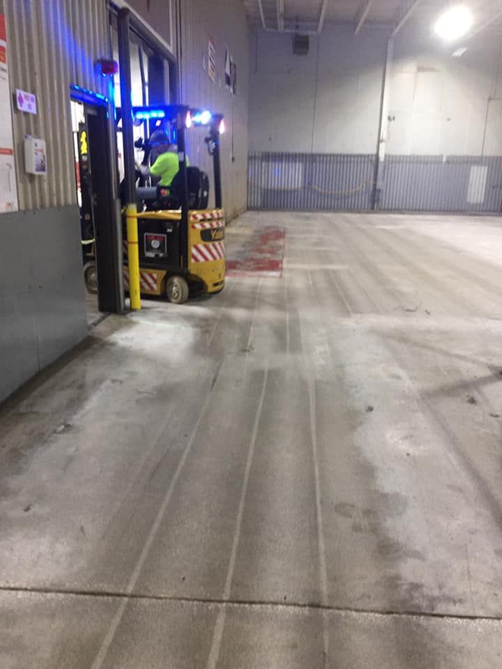 A man is driving a yellow forklift in a warehouse.