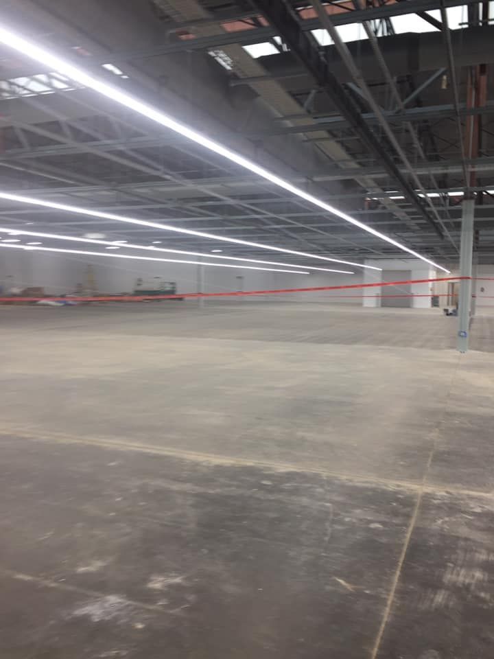 A large empty warehouse with a lot of lights on the ceiling.