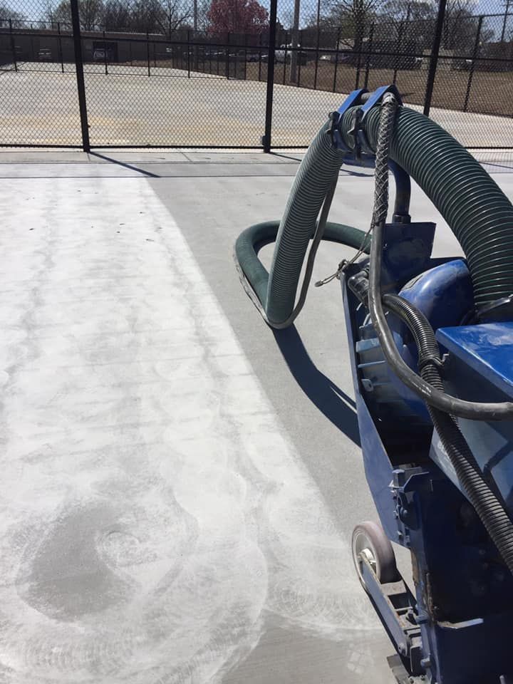 A machine is cleaning a tennis court with a hose attached to it.