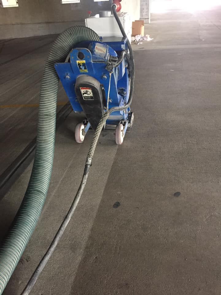 A vacuum cleaner is being used to clean a parking garage floor.