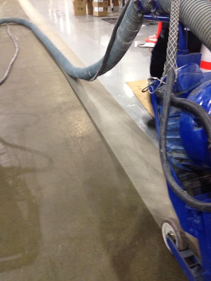 A blue vacuum cleaner is being used to clean a concrete floor