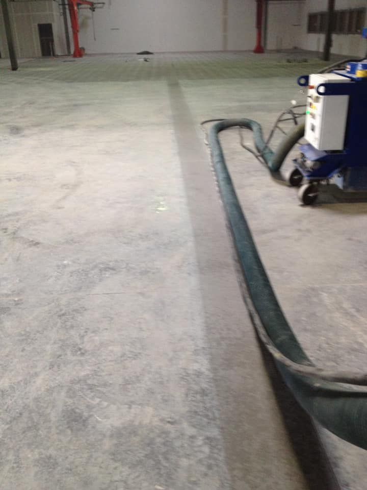 A machine is cleaning a concrete floor in a warehouse.