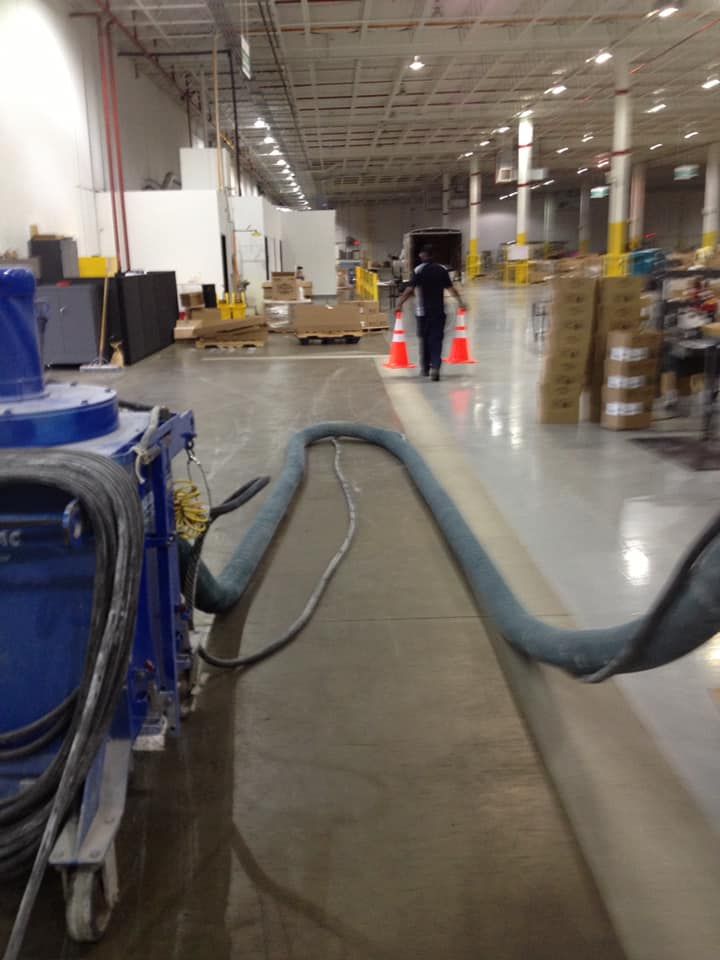 A man is walking through a warehouse with a hose attached to him