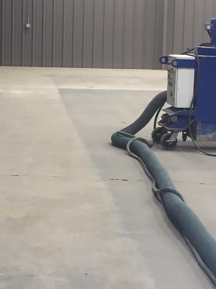 A blue and white machine is sitting on a concrete floor.
