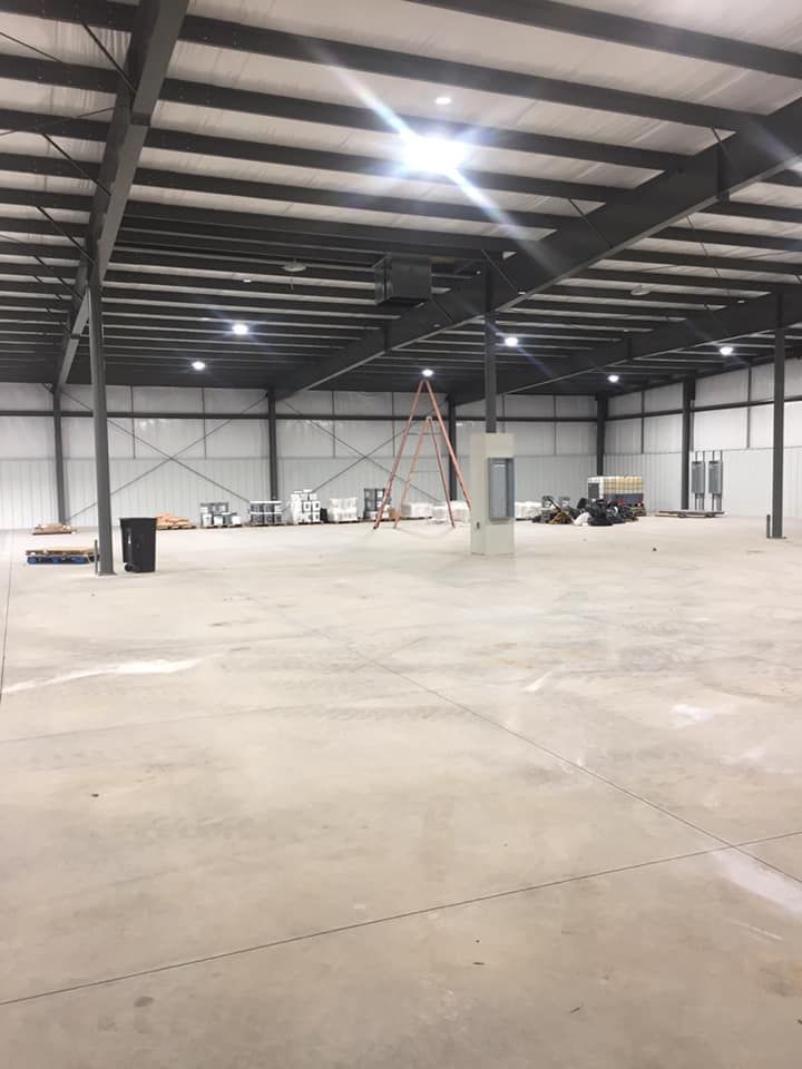 A large empty warehouse with a ladder in the middle of it.