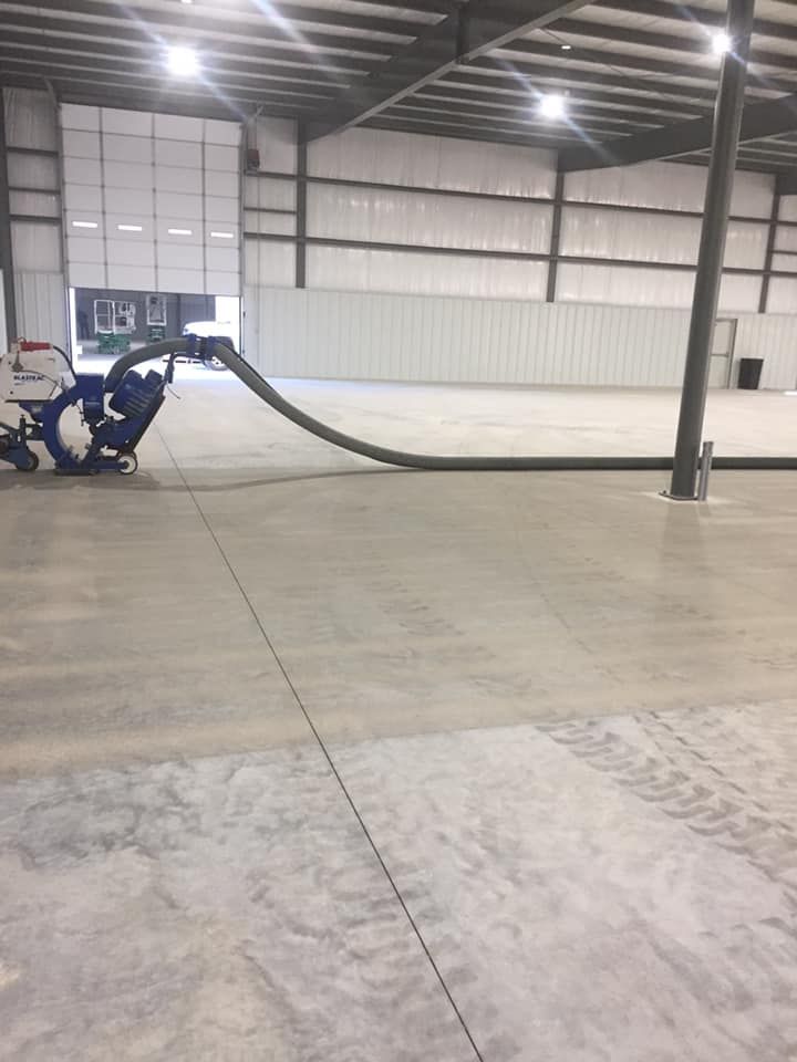 A machine is being used to clean a concrete floor in a warehouse.