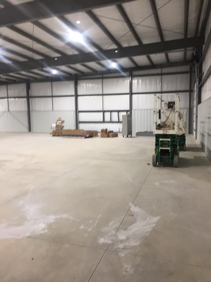 A large empty warehouse with a green lift in the middle