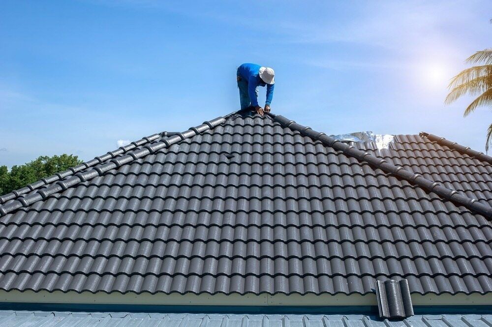 A Man is Working on the Roof of a House — Wagga Roof Repairs In Mount Austin, NSW