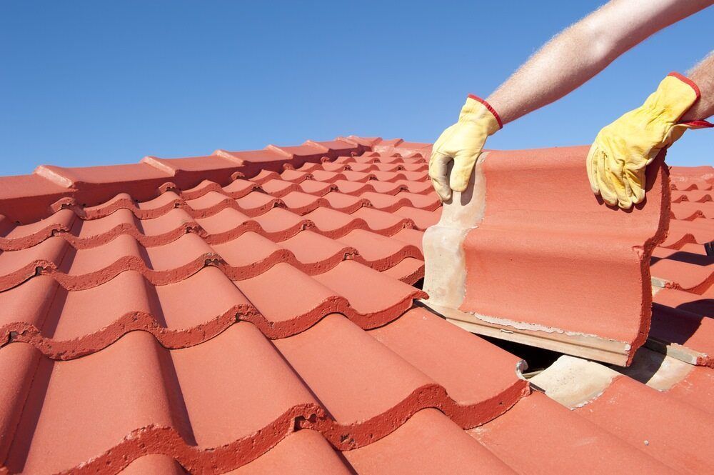 A Person Wearing Yellow Gloves is Working on a Roof — Wagga Roof Repairs In Mount Austin, NSW