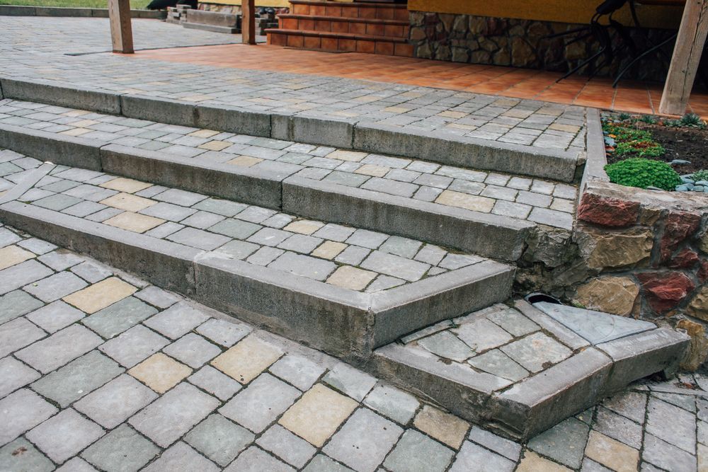Stone steps leading up to a building, with a paved walkway.
