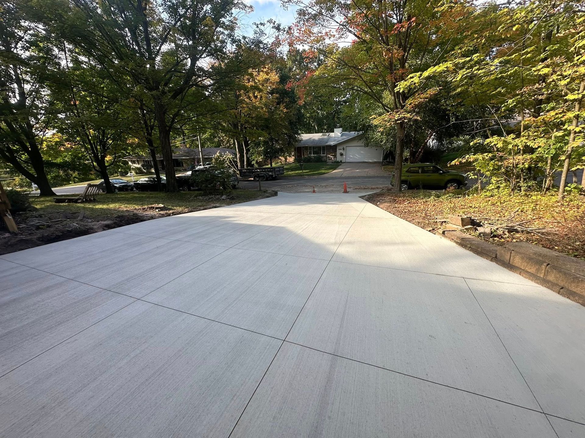 Newly paved concrete driveway leading to a house, surrounded by trees.