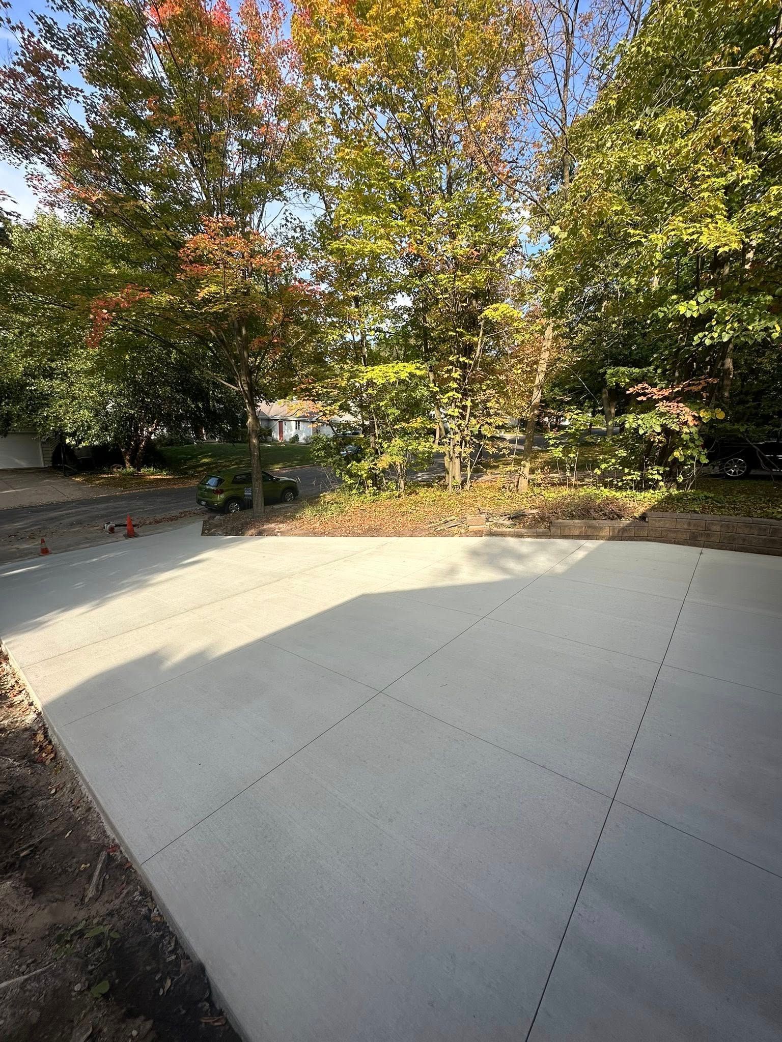 New concrete patio with trees in the background under a blue sky.