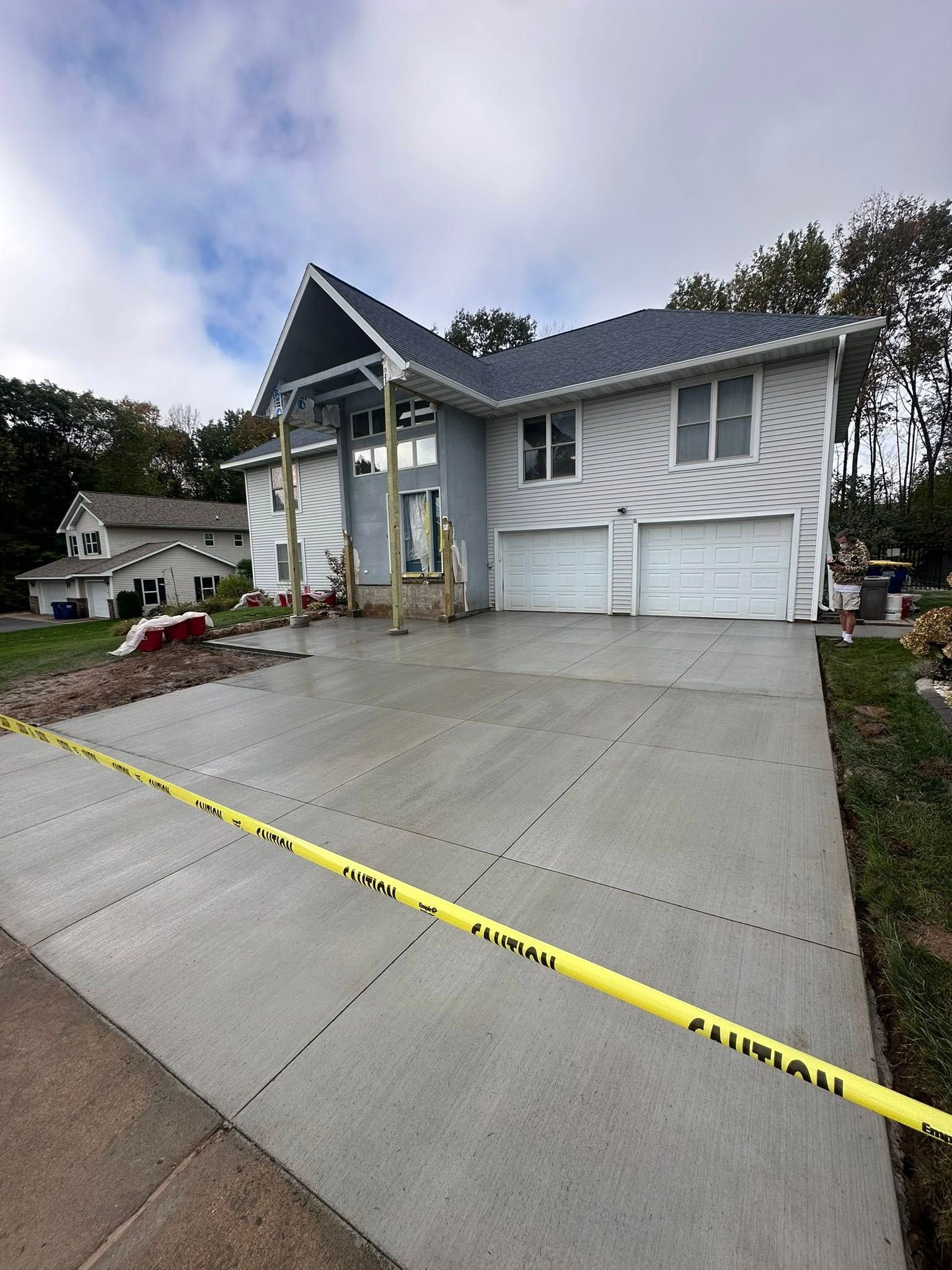 House with new concrete driveway under construction, with caution tape.