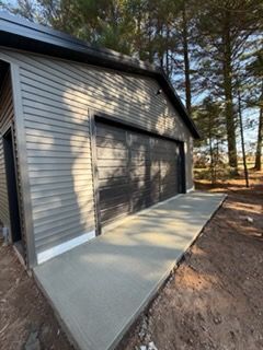 Covered porch with stone columns, wood door, and grey siding.