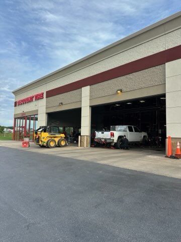Empty parking lot in front of a strip mall with a cloudy sky.
