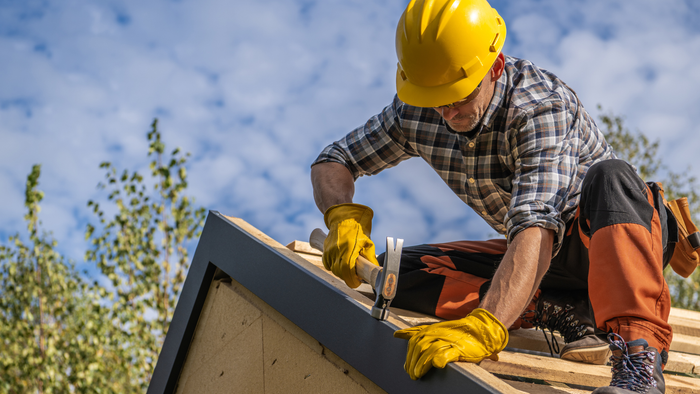 A man is working on a roof with a hammer and nails. A man is working on a roof with a hammer and nails.