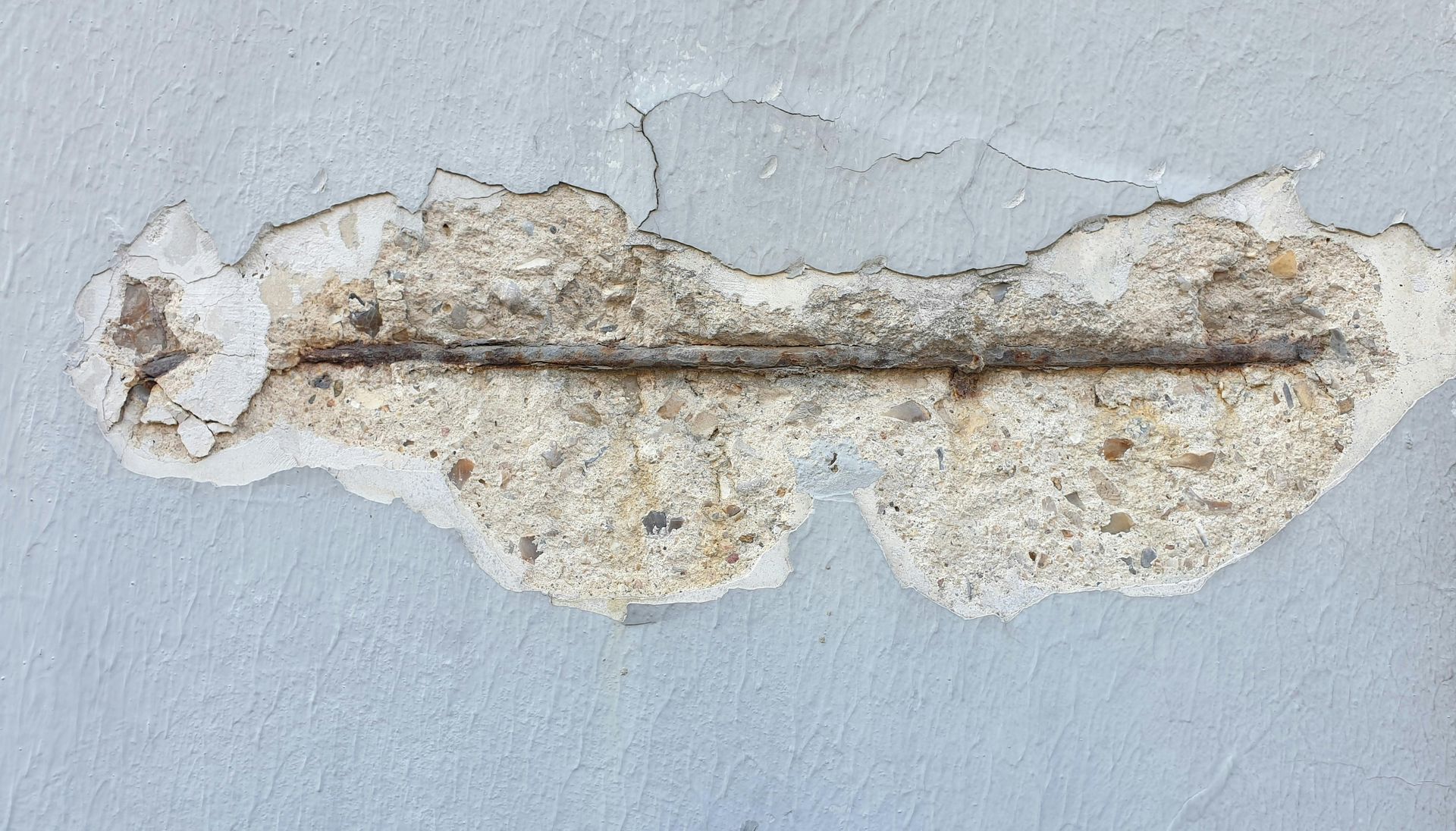Chipped white wall paint revealing a long horizontal crack and exposed plaster underneath.