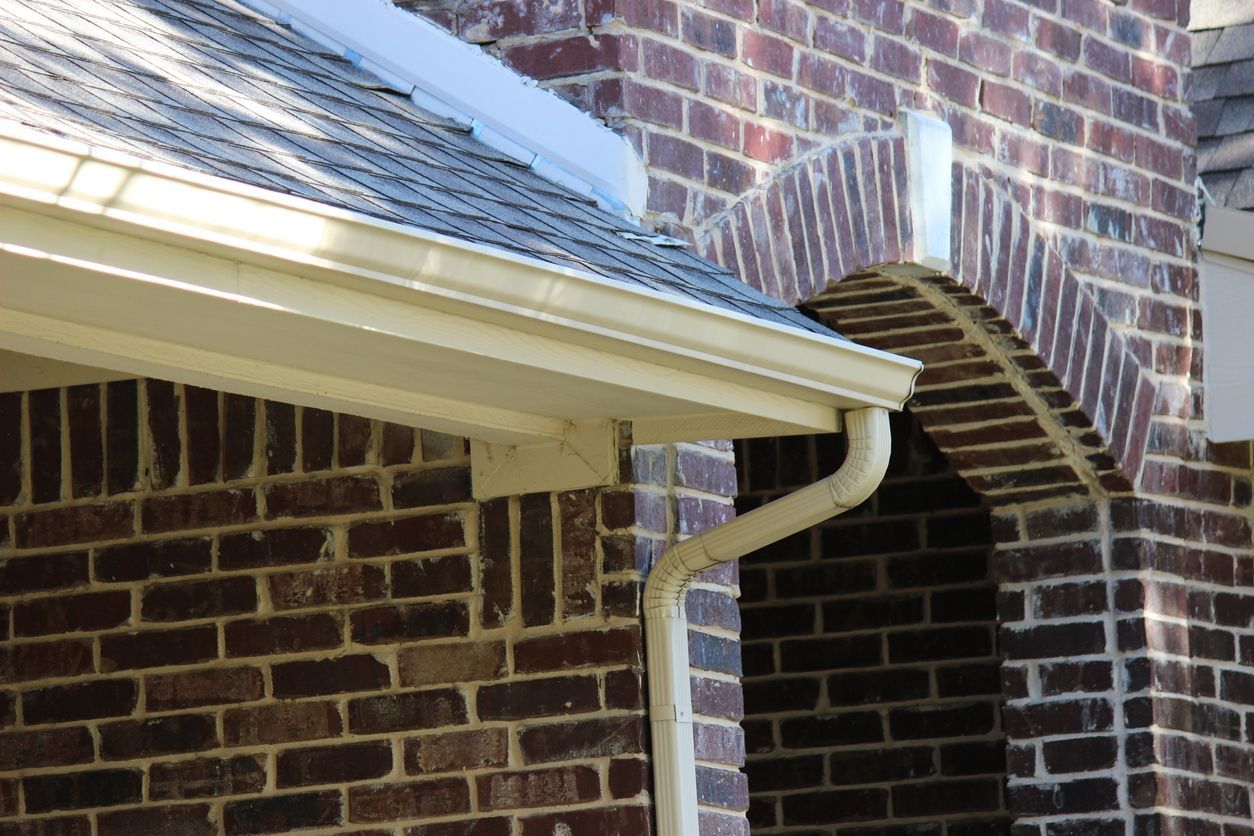 White gutter on a brick building with a roof overhang.