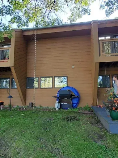 Brown apartment building exterior with grill, grass, and a person on the right.