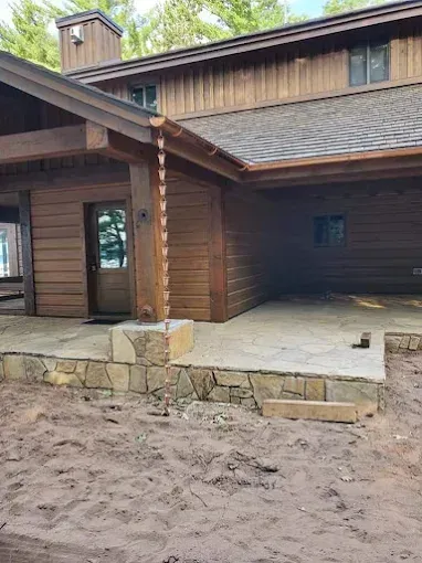 Brown cabin exterior with stone patio and a rain chain.