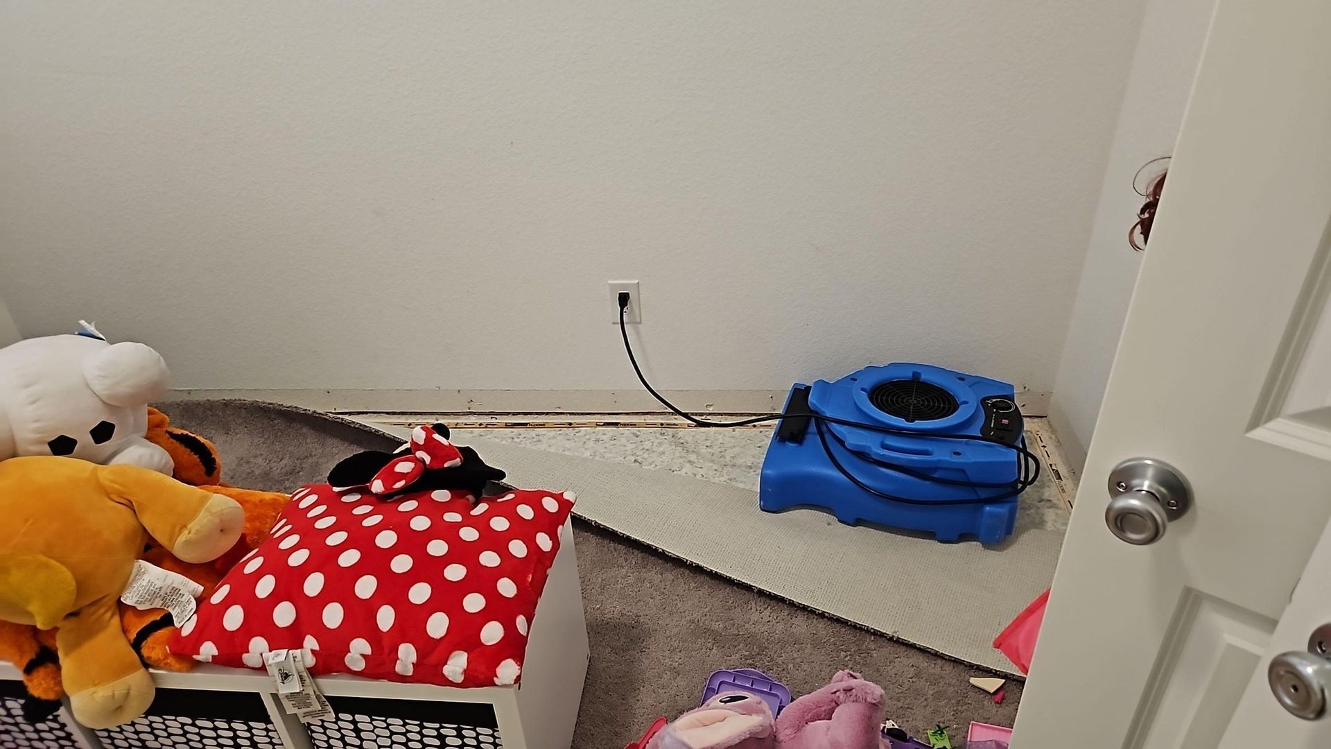 Drying equipment positioned under bedroom carpet for water damage mitigation