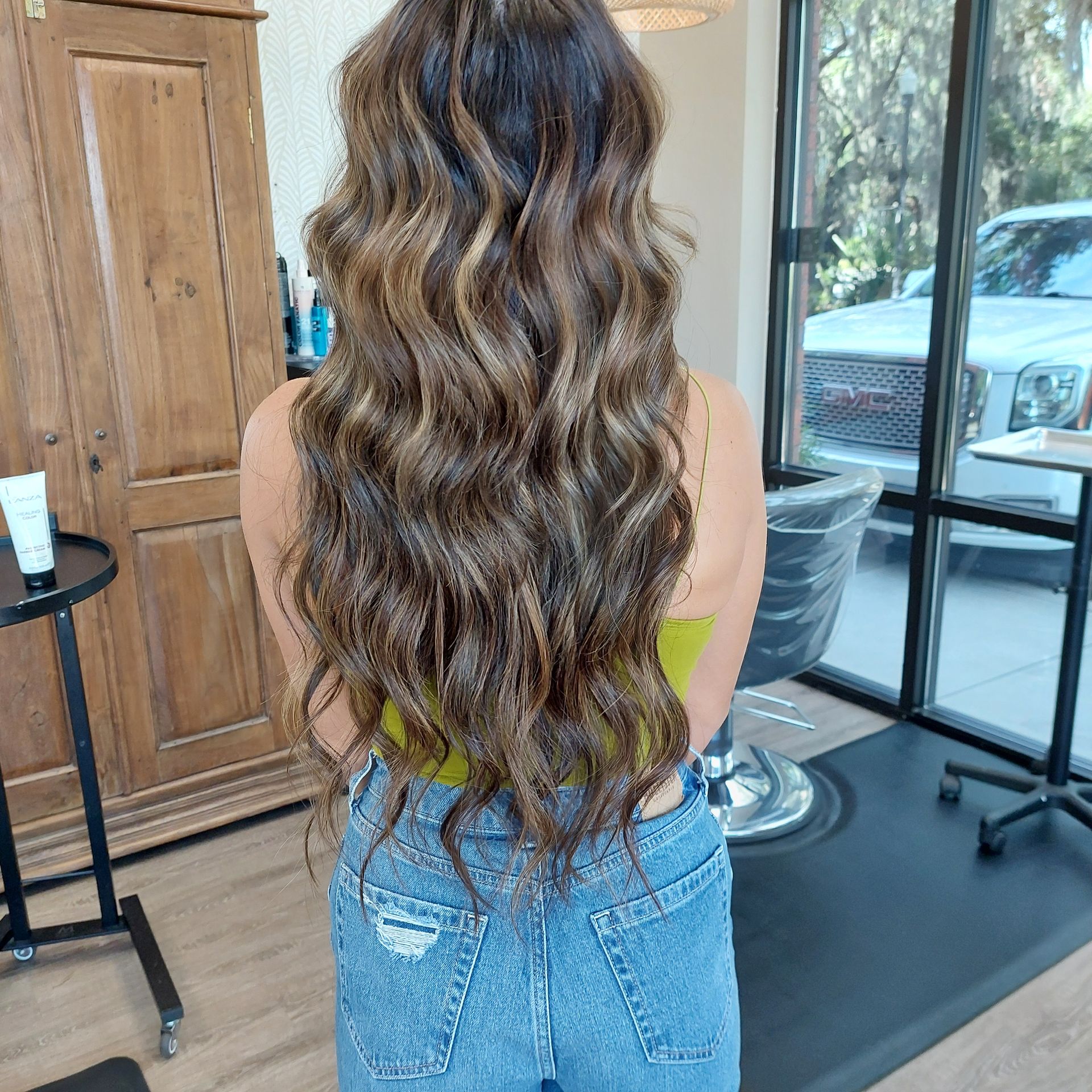 A woman is getting her hair extensions done at a salon.