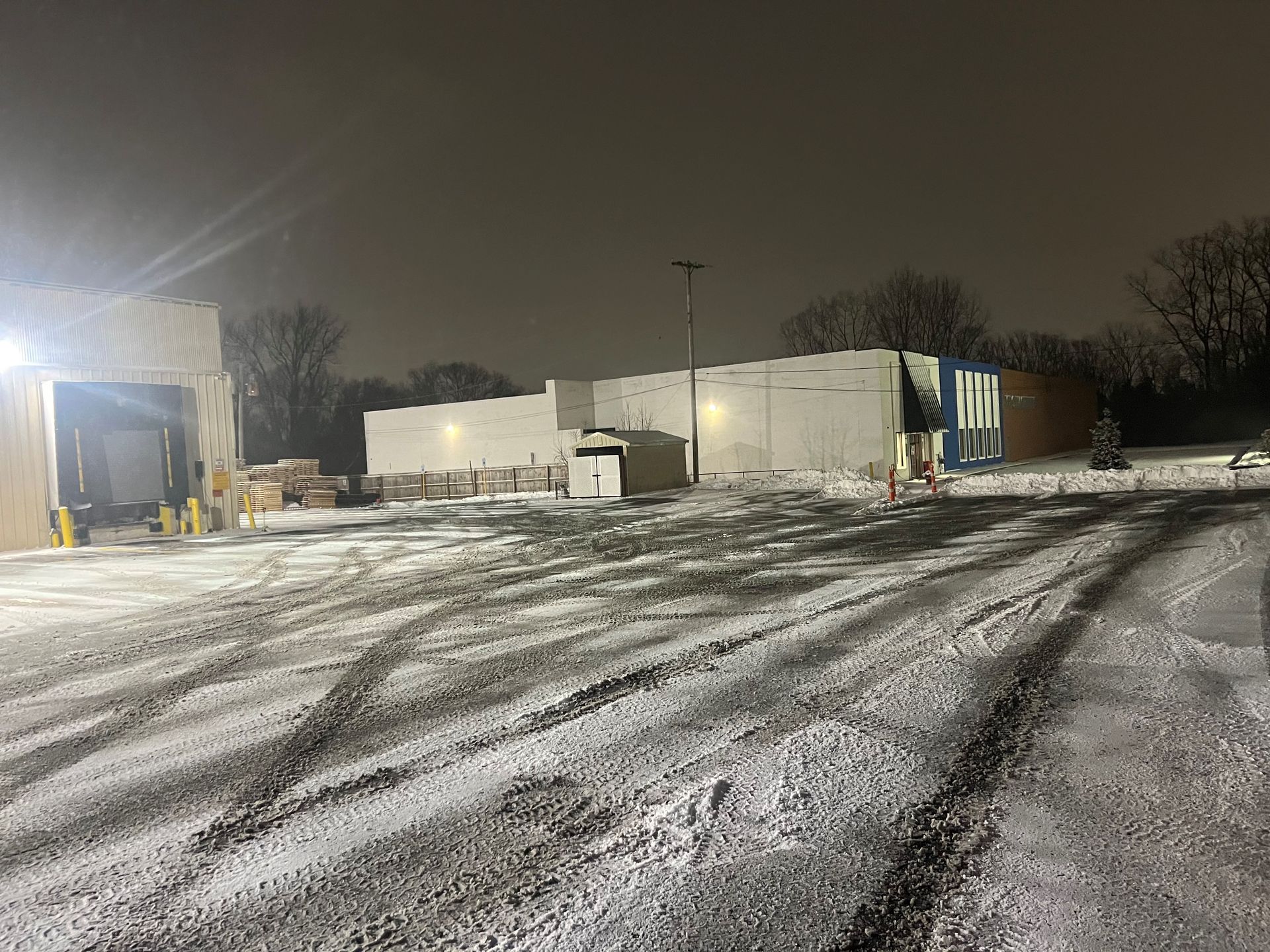 A parking lot covered in snow at night with a building in the background.