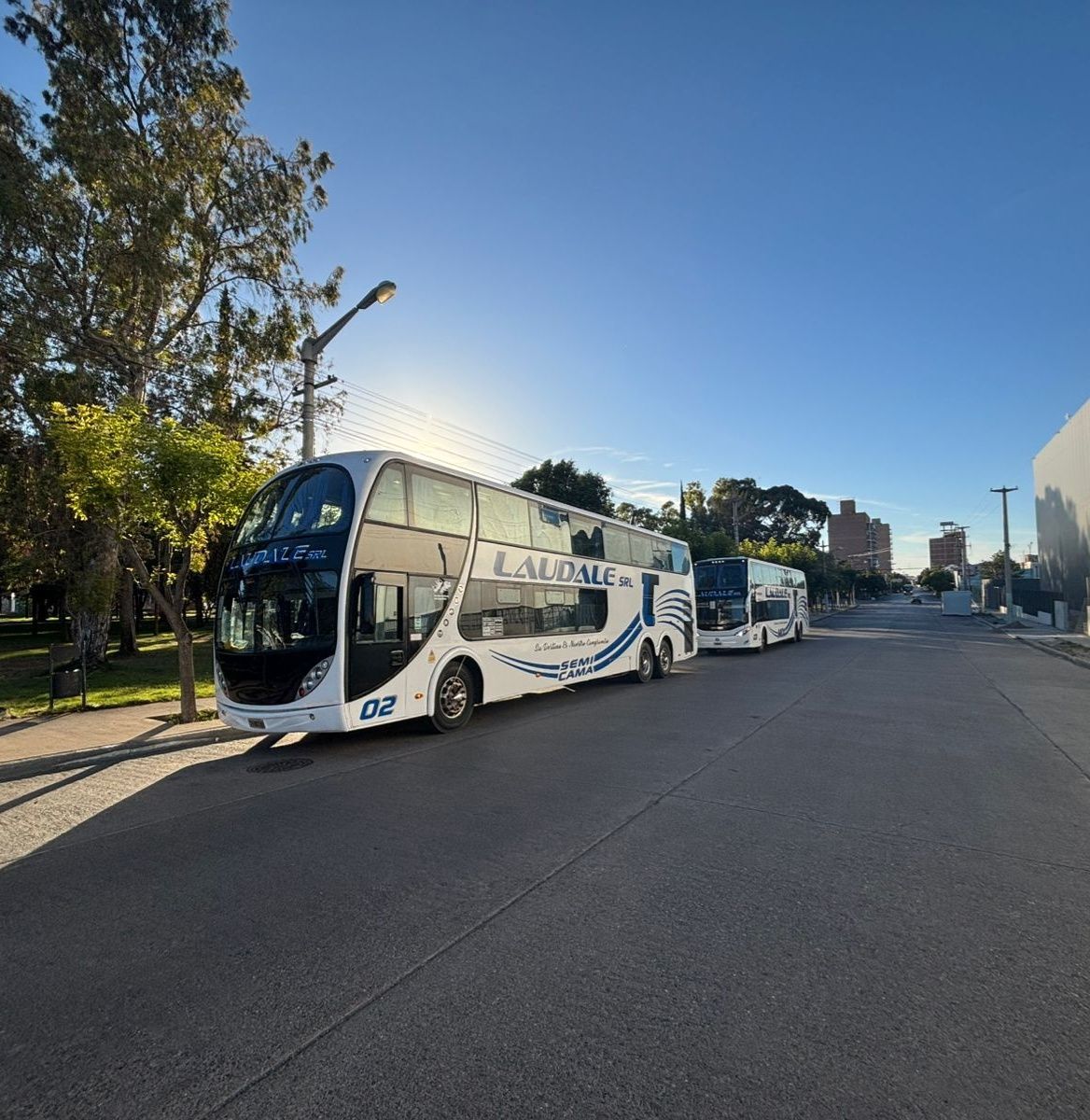 Autobuses de dos pisos estacionados en una calle pavimentada bajo un cielo azul brillante.