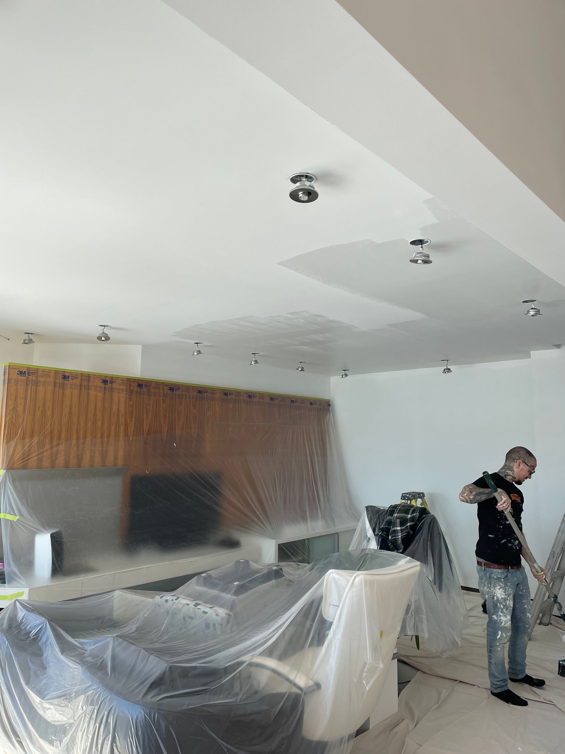 Un homme peint le plafond d'un salon