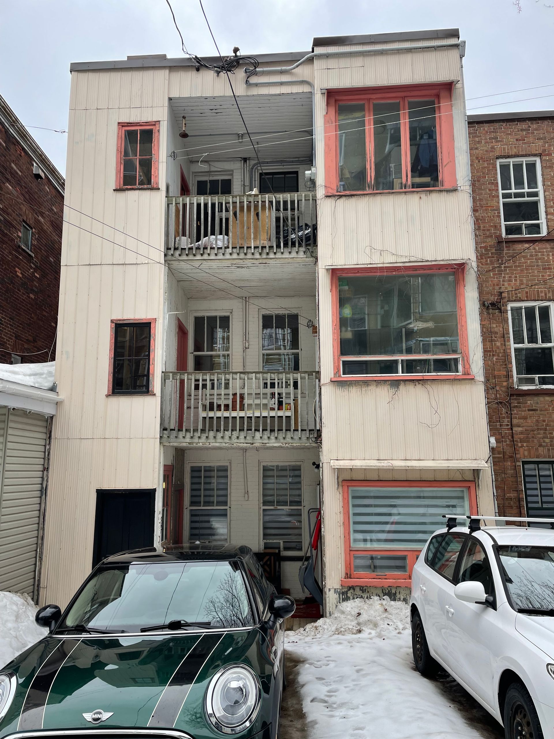 Une mini cooper verte est garée devant un immeuble.